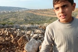 Syrian boy stands near Scud missile crater