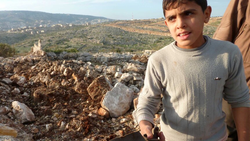 A Syrian boy displays what is claimed to be remains of Scud missile