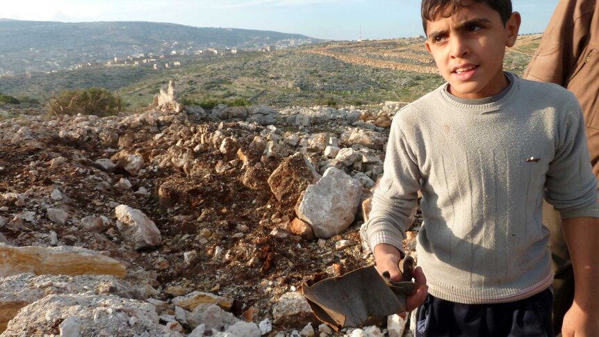 Syrian boy stands near Scud missile crater