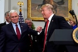 Mike Pence escorts US President Donald Trump back towards the table behind podium