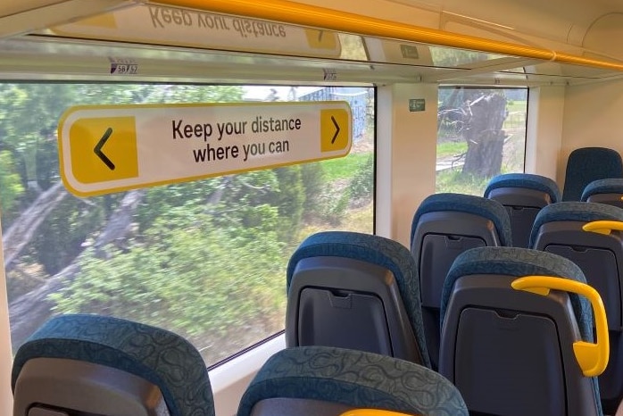 One person sits on a train carriage between Geelong and Melbourne. A sign tells people to "keep your distance where you can".
