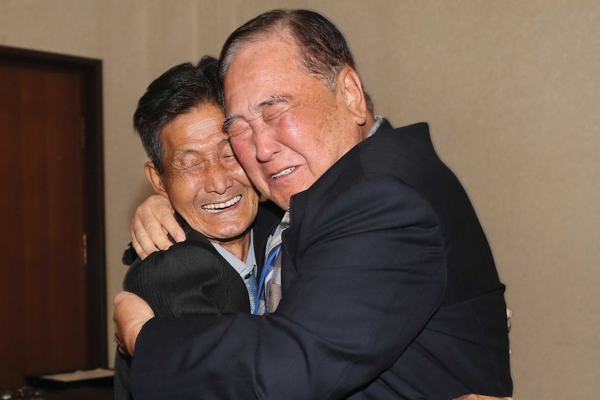 Two men emotionally embrace.