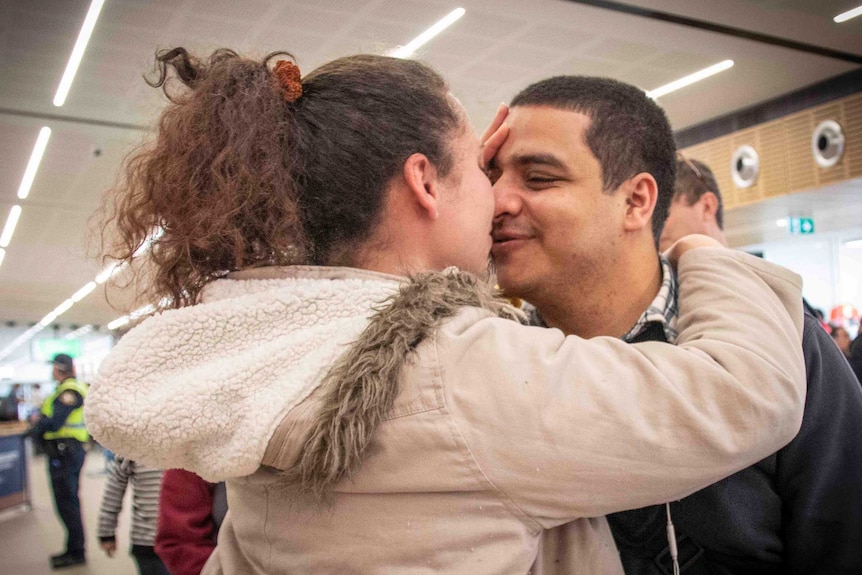 A couple embrace at an airport arrivals lounge