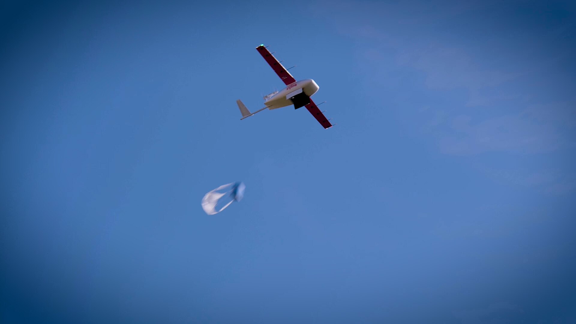 A delivery drone carrying a plastic bag in the sky.