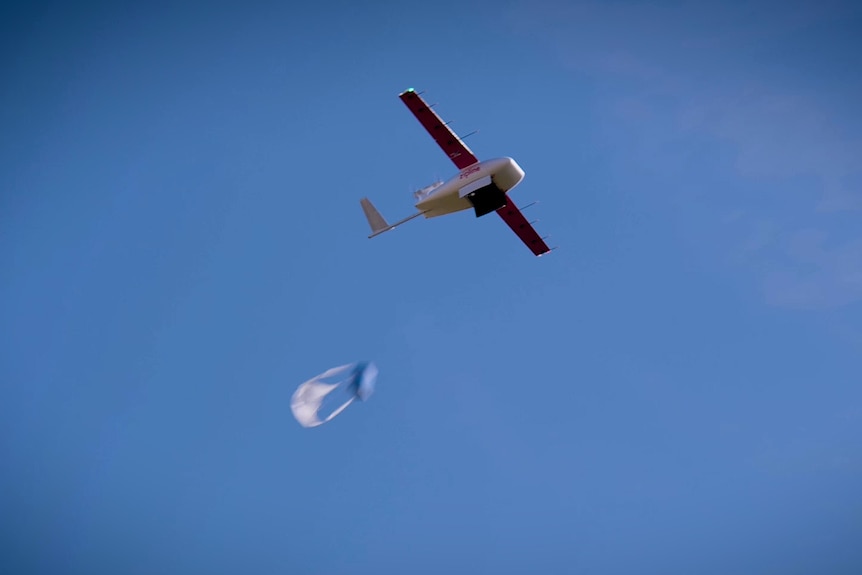 A delivery drone carrying a plastic bag in the sky.