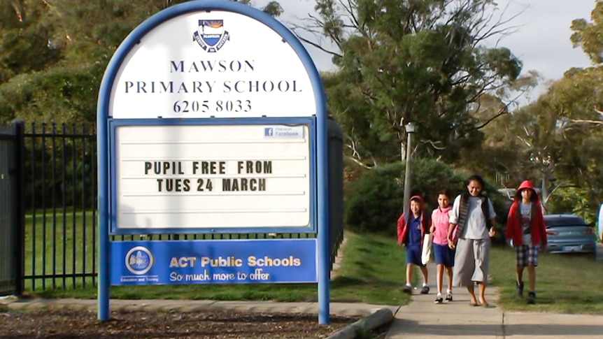 A family walks past a school sign.