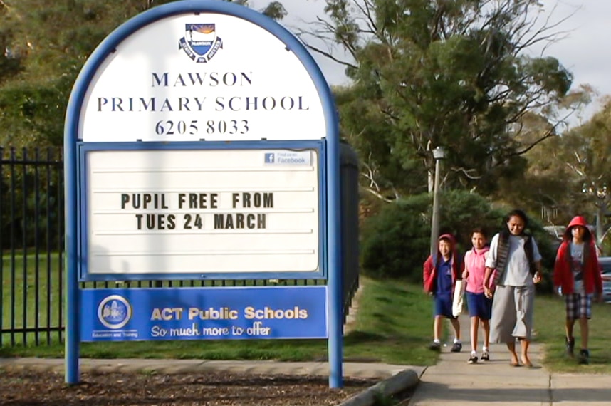 A family walks past a school sign.