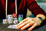 Gambling chips and cards behind a male hand