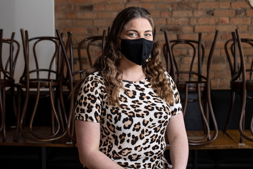 A woman sits on a chair in a closed cafe.