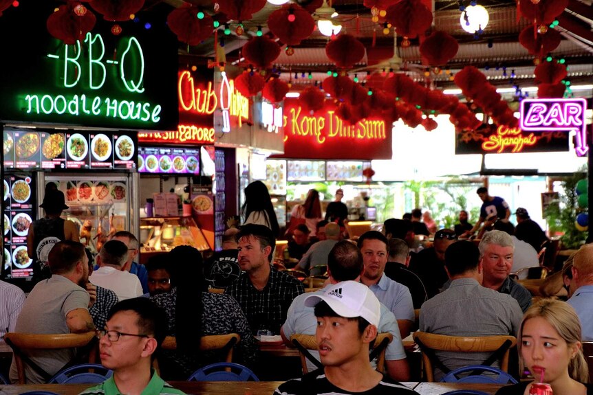 A busy food court with Chinese lanterns hanging from the roof