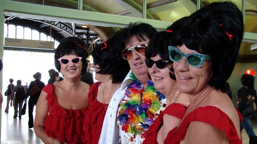 An Elvis impersonator and 'fans' pose for photos before leaving Sydney's Central Station
