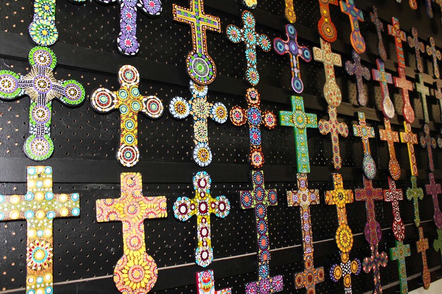 Small painted crosses hang on a wall.