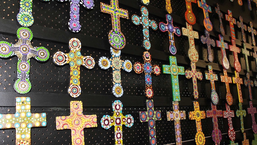 Small painted crosses hang on a wall.