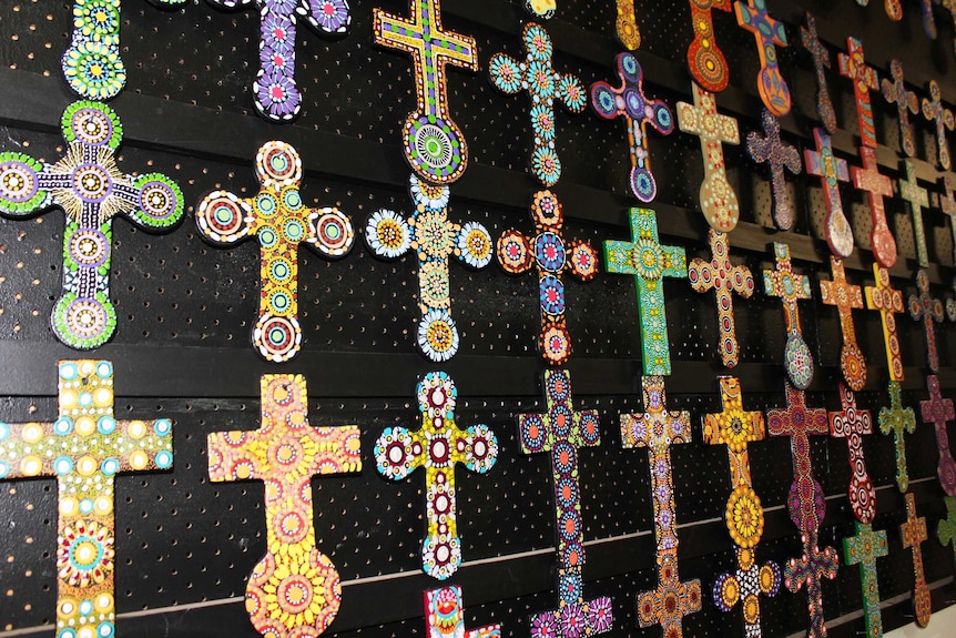 Small painted crosses hang on a wall.