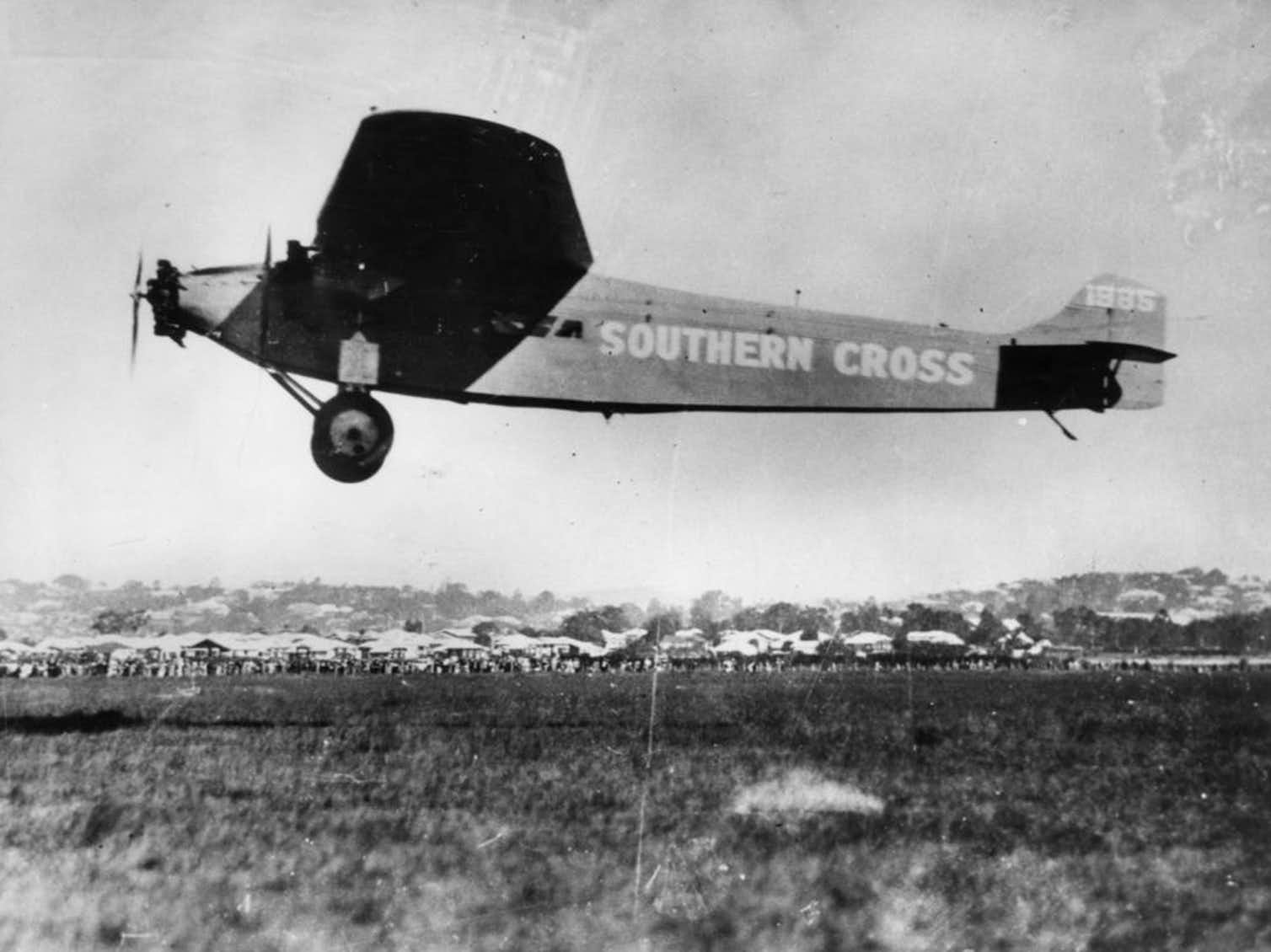 A black and white photo of a small plane bearing the text 'SOUTHERN CROSS' in white paint