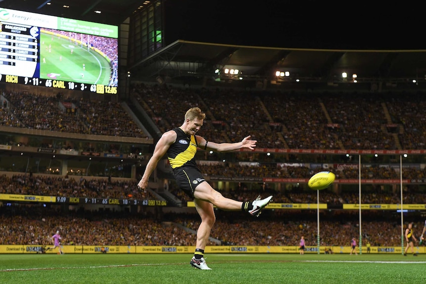 The ball flies off the boot of a Richmond player as he kicks for goal at the MCG.
