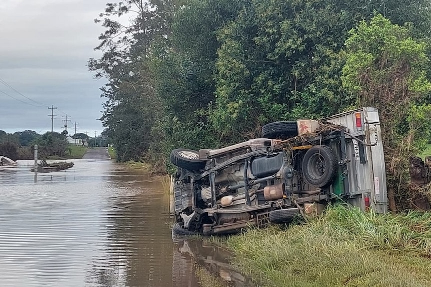 A car on its side in flooded water.
