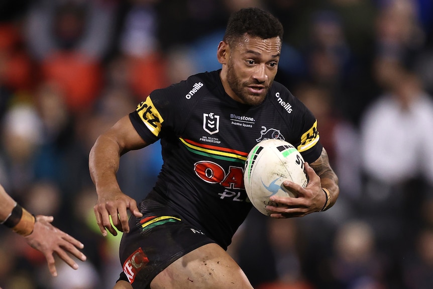 A man runs the ball during a rugby league match