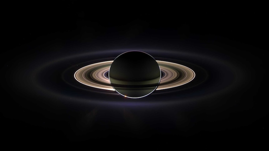 Saturn is shown with its rings backlit by the Sun behind it