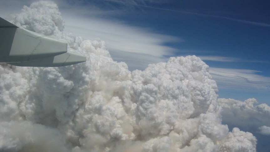 Bushfire smoke billows in the air like clouds. The photo is taken from inside a plane