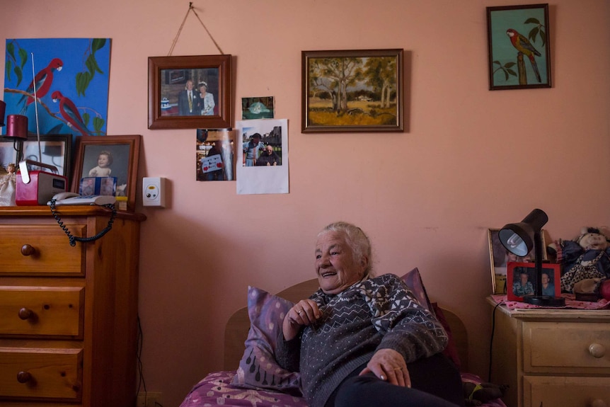 Bev Howlett with pictures on the wall above head at the Wintringham Aged Care Hostel in Williamstown, Victoria.