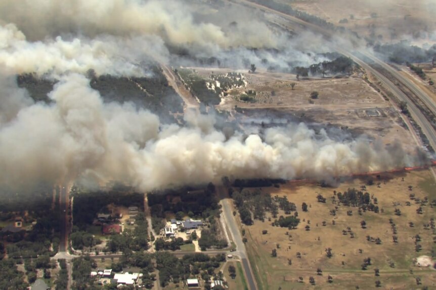 An aerial image of smoke billowing over homes and a freeway