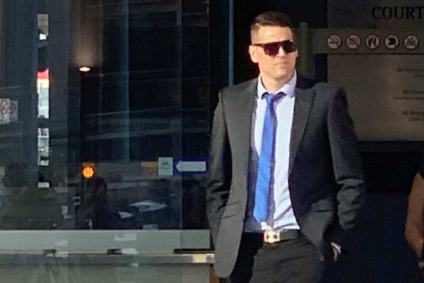 Matthew Paul Hockley, dressed in a suite and sunglasses, leaves the District Court building in Brisbane.