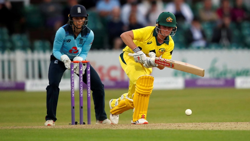 Beth Mooney hits a shot off the front foot as the England wicketkeeper watches on