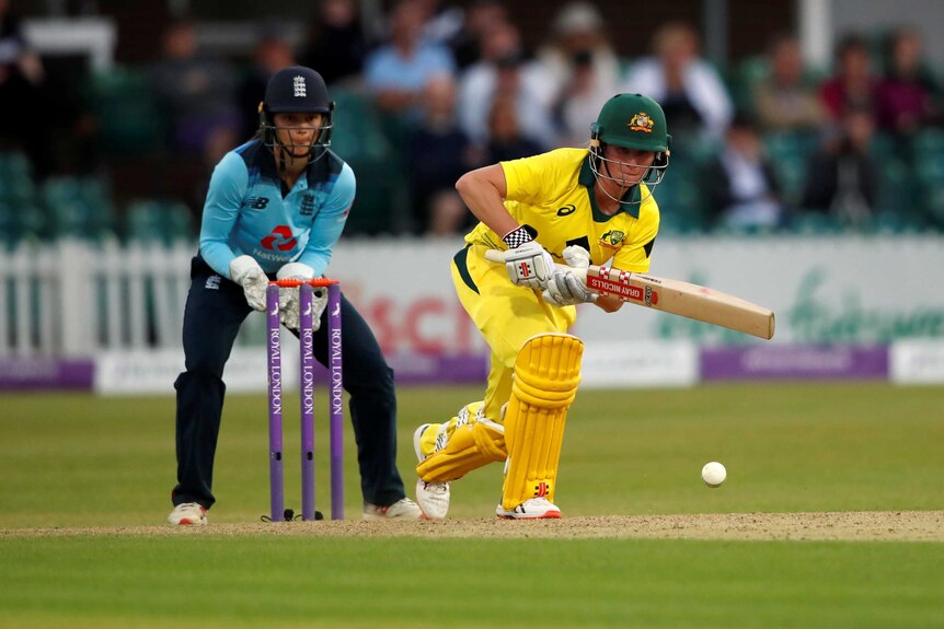 Beth Mooney hits a shot off the front foot as the England wicketkeeper watches on