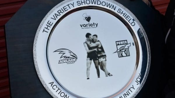 A silver plate with two football players hugging, the logos of Adelaide Crows, Variety SA and Port Adelaide. 