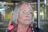 A woman with grey hair standing in front of a revolving door