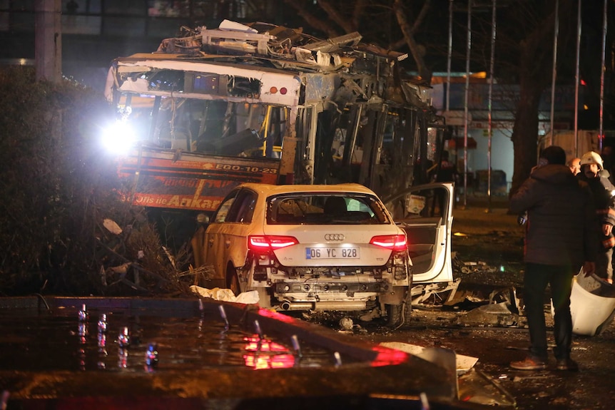 A man stands next to a burnt out bus after a blast in Ankara.