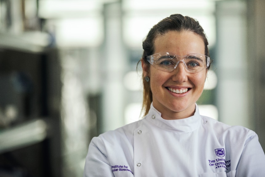 blonde woman wearing safety glasses and white lab coat