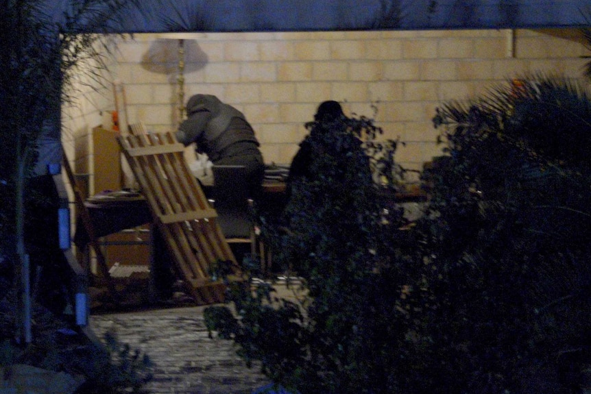 Officers search the garage of a home raided by police in Greenvale