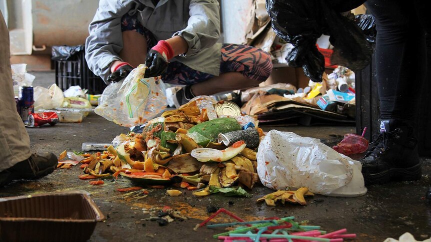A photo of food waste surrounded by volunteers in a shed.