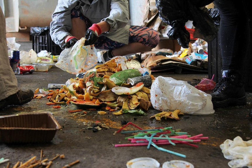 A photo of food waste surrounded by volunteers in a shed.