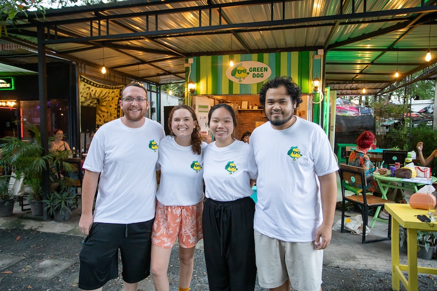 A group of four people pose in front of the Green Dog cannabis store. 