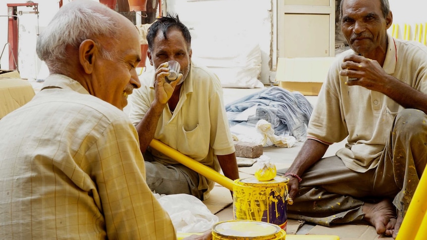 Workers painting cricket stumps taking a chai break