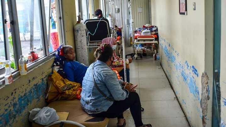 Several patients in Indonesia are pictured sitting in a emergency room, waiting to be seen. 