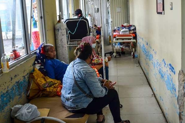 Several patients in Indonesia are pictured sitting in a emergency room, waiting to be seen. 