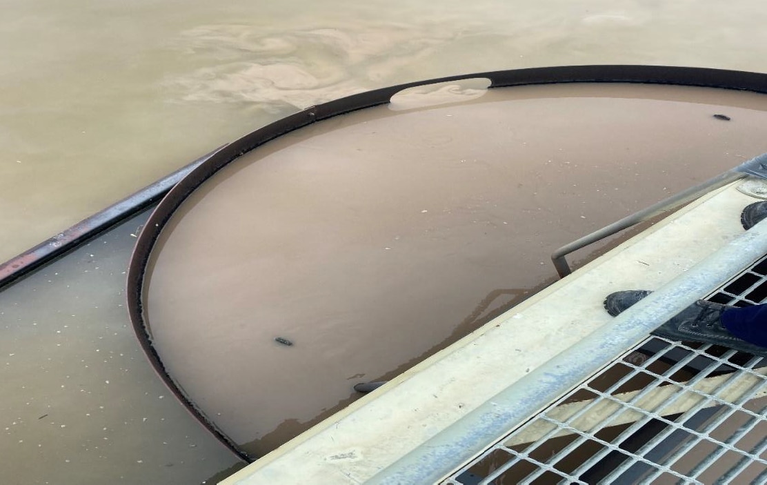 Agua turbia gris en un recipiente junto a un cuerpo de agua y grárese