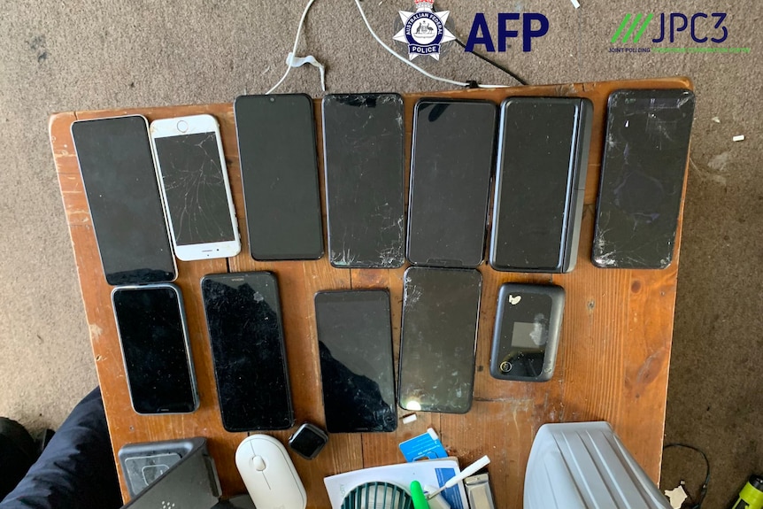 Phones are lined up on a table.