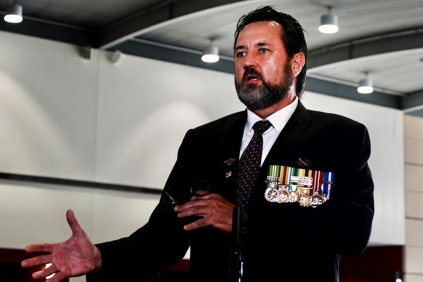Former Australian serviceman Simon Marshall speaks, while dressed in a suit wearing his military medals.