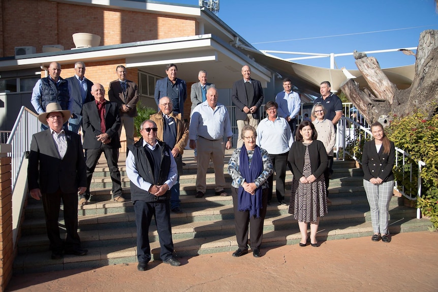 A group of council mayors wearing business attire stand on the steps outside a council building