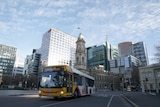 A bus on a city street with buildings behind