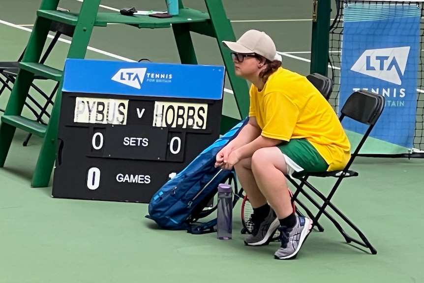A tennis player sitting on the sidelines of a court