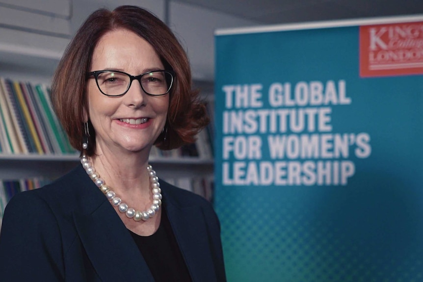 Julia Gillard smiles for a portrait in front  of a King's college promo sign