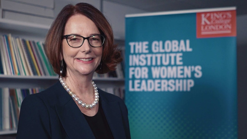 Julia Gillard smiles for a portrait in front  of a King's college promo sign