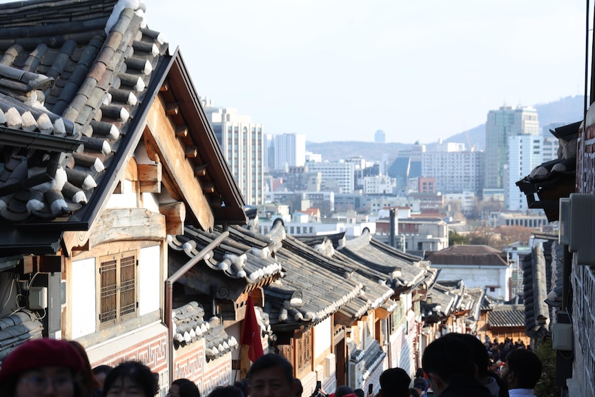 A traditional South Korean building in foreground against a background of modern buildings and high rises 