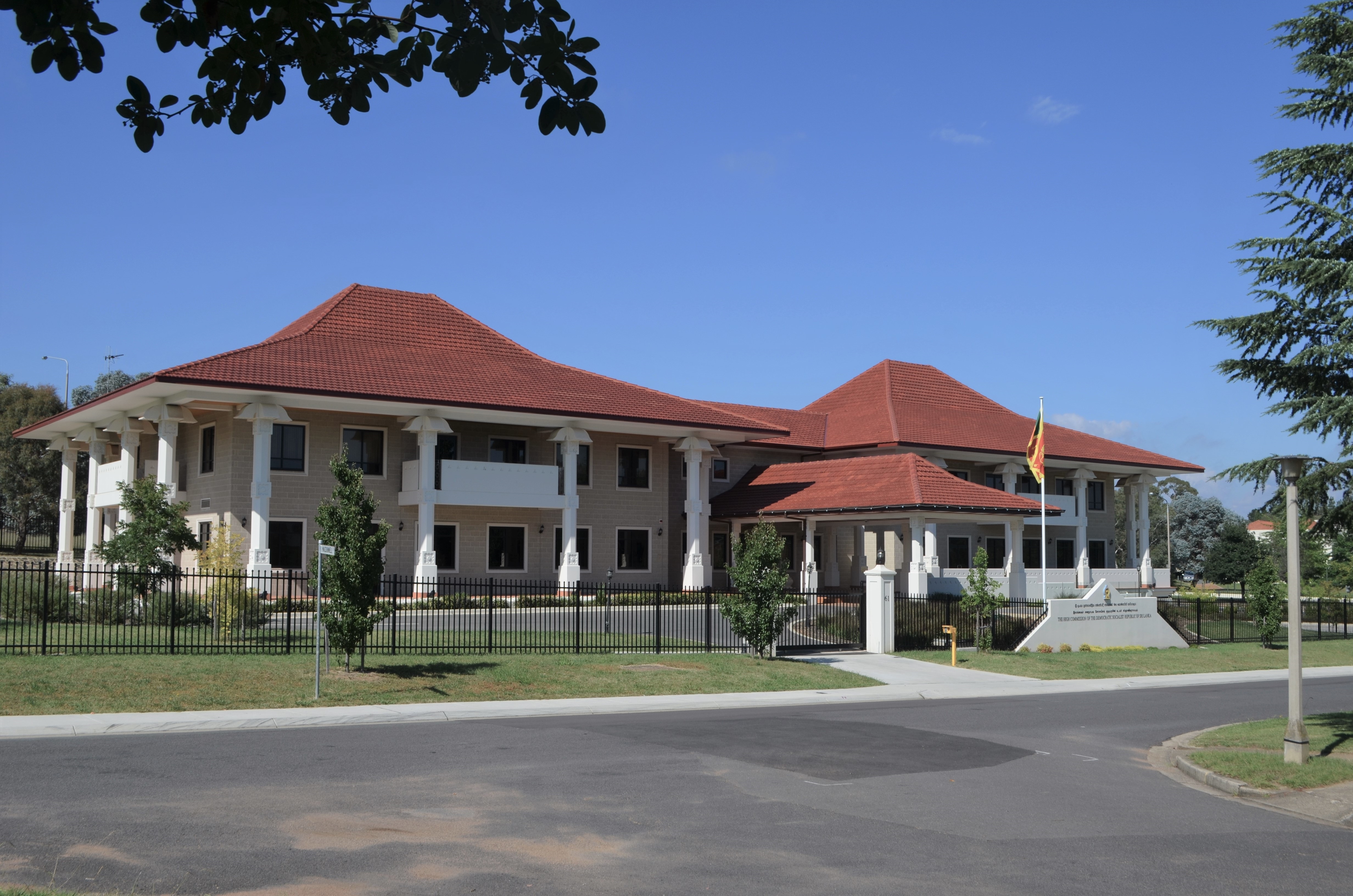 A two-storey building with red roofs and white columns with a flag in the front